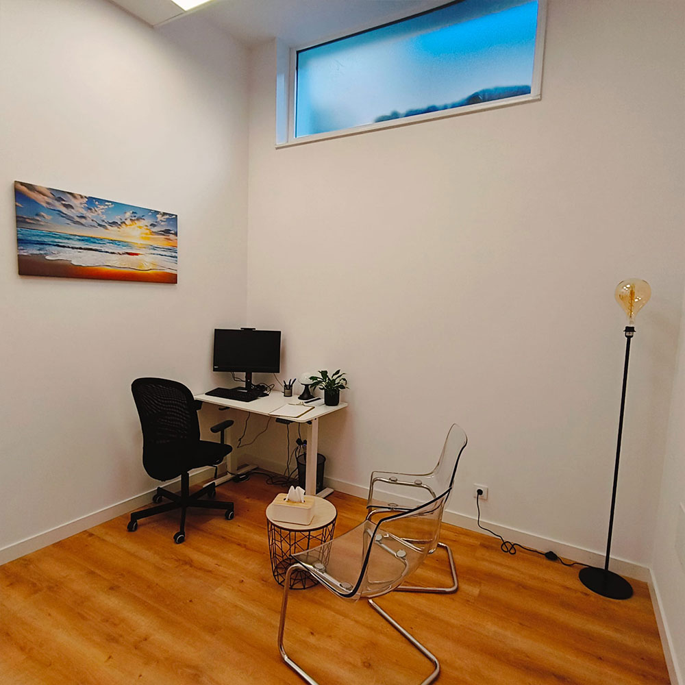 Consulta médica privada en clínica sanitaria con escritorio, sillas para paciente, iluminación cálida y ambiente tranquilo.