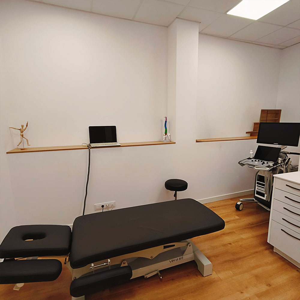 Consulta médica privada en clínica sanitaria con escritorio, sillas para paciente, iluminación cálida y ambiente tranquilo.