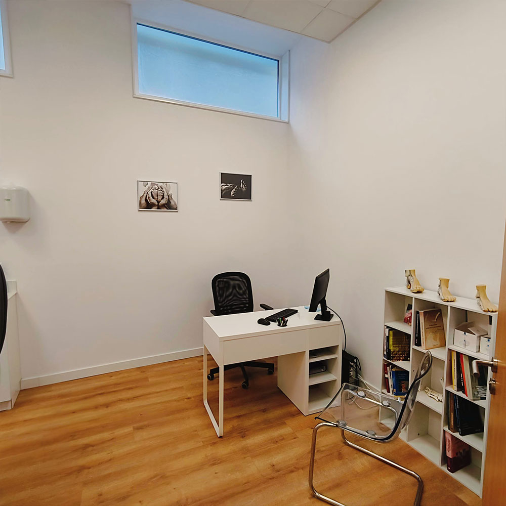 Consulta médica privada en clínica sanitaria con escritorio, sillas para paciente, iluminación cálida y ambiente tranquilo.
