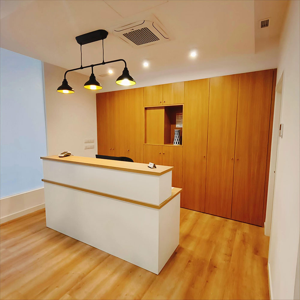 Recepción en clínica sanitaria con escritorio, silla, iluminación cálida y ambiente tranquilo.