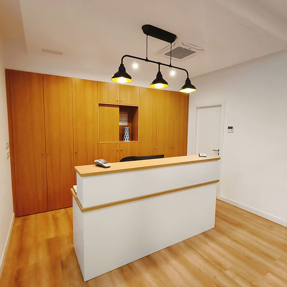 Recepción en clínica sanitaria con escritorio, silla, iluminación cálida y ambiente tranquilo.