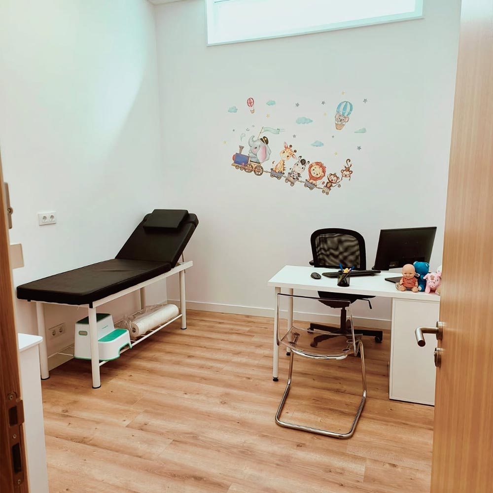 Consulta de pediatría en Clínica Ribadavia, espacio infantil con camilla médica, escritorio y decoración para niños