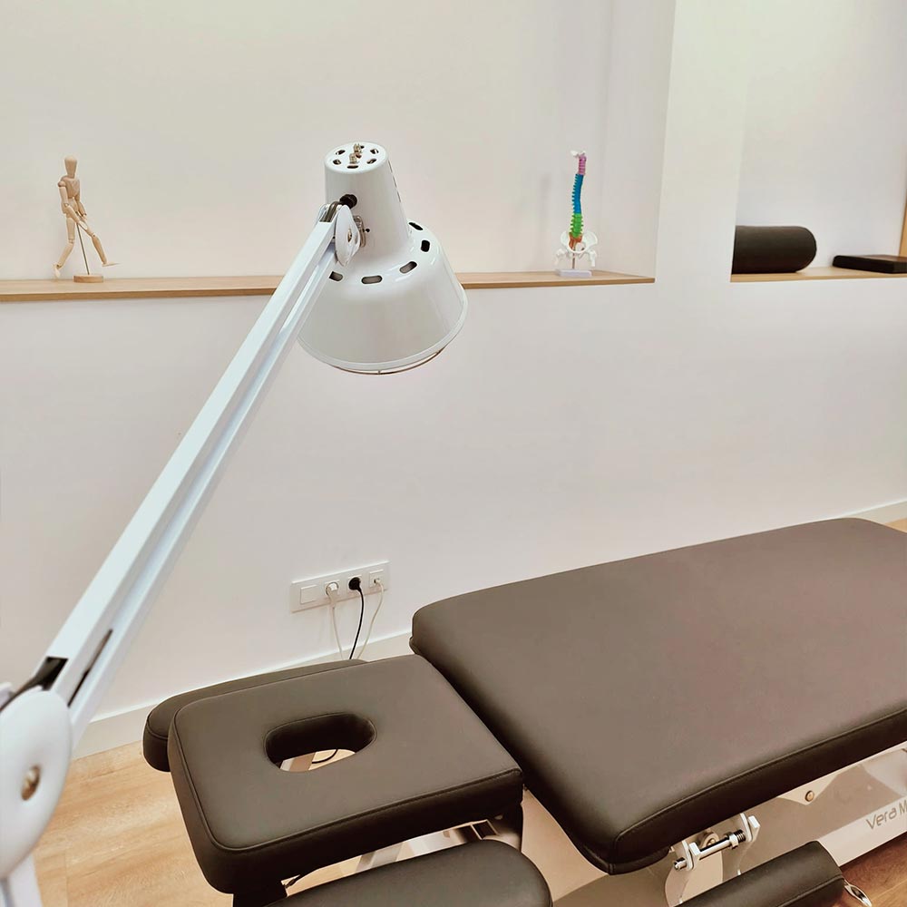 Camilla de fisioterapia en Clínica Ribadavia con lámpara de exploración y equipamiento para tratamiento terapéutico