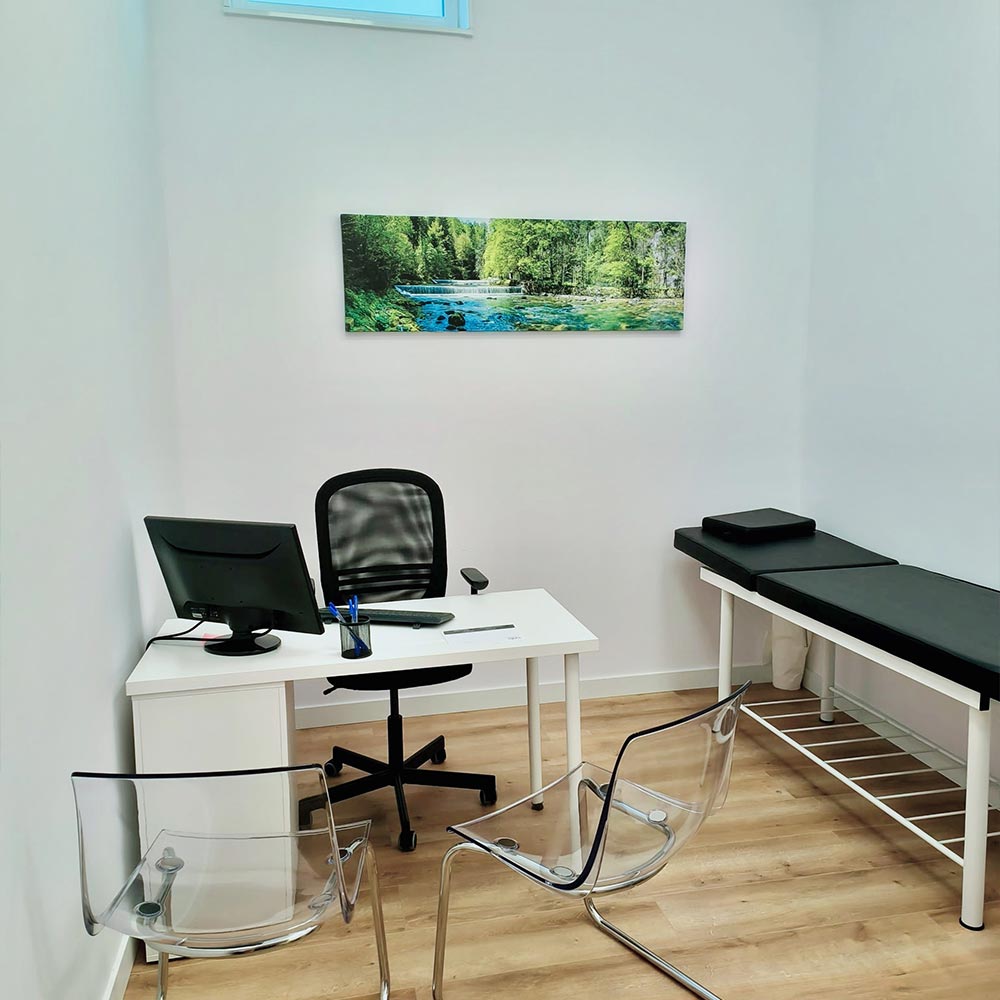 Consulta médica de Clínica Ribadavia con escritorio, camilla de exploración y ambiente moderno y luminoso